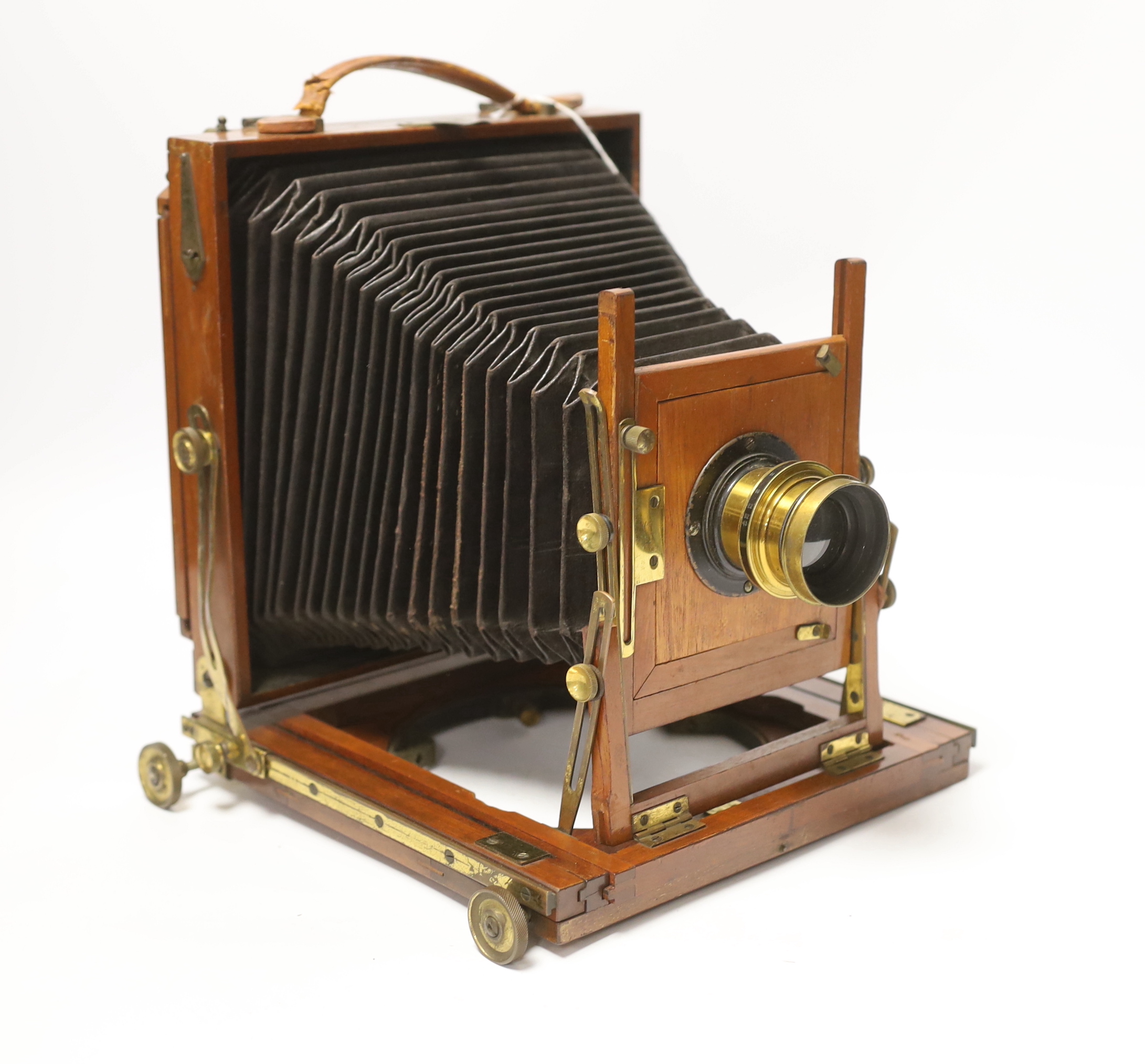 A late nineteenth century brass and mahogany half plate bellows camera with a lens and a shutter action by Taylor, Taylor & Hobson, Leicester, together with a negative holder